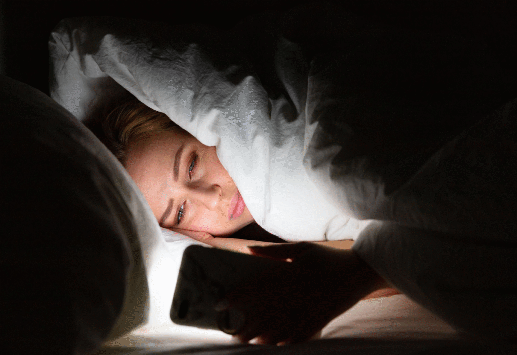 Woman awake at 3am during perimenopause, struggling with insomnia while looking at her phone